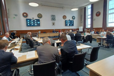 The full council meeting showing councillors sitting at tables in the chamber