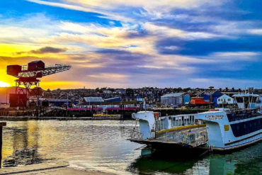 Floating bridge crossing the rover medina with hammerhead crane and sunset in the background