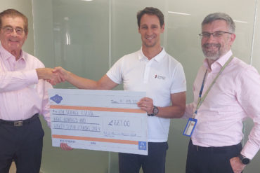 Three men posing for the camera with a giant cheque