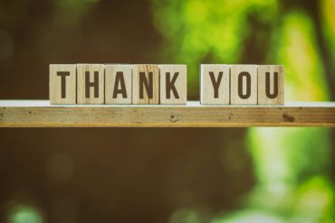 wooden blocks with letters on spelling 'thank you' with green background