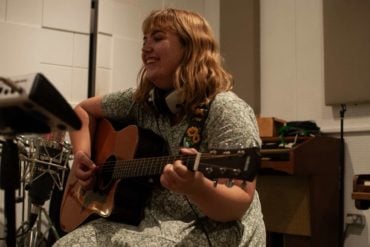 Amy Jolliffe playing guitar in the studio