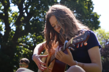 Female teenager playing a guitar in the park