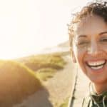 image of woman smiling with the sun inthe background