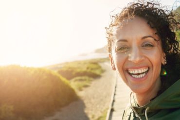 image of woman smiling with the sun inthe background