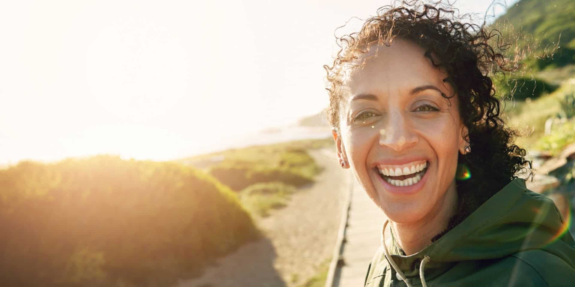 image of woman smiling with the sun inthe background
