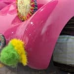 A pink car bonnet decorated with knitted items