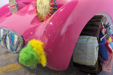 A pink car bonnet decorated with knitted items