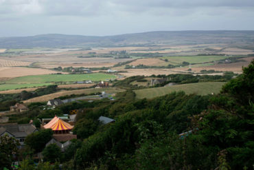 Drone landscape picture of the Isle of Wight. Lush greenery and a small, orange striped circus tent