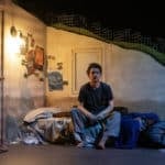 Man on stage in bedroom scene - sat on his bed