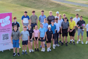 Group of children on golf course with banner about fighting mitochondrial diseases