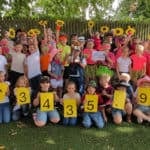 Pupils from Carisbrooke Primary holding sunflowers and large cards with the amount raised