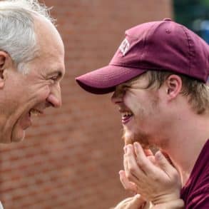 An older man smiling with a man with downs syndrome by nathan anderson
