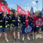 FBU members protesting against cuts, holding FBU flags outside the fire station