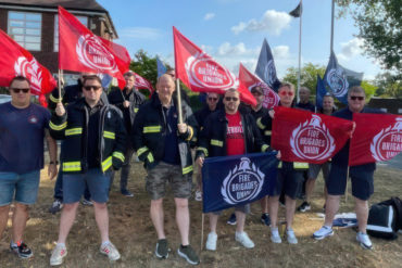 FBU members protesting against cuts, holding FBU flags outside the fire station