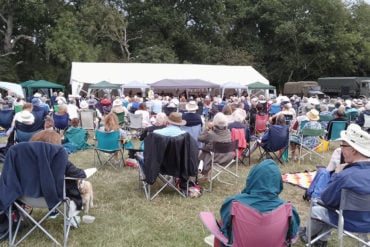 The audience (sitting in fold up chairs) at the symphony orchestra concert at Havenstreet Steam Railway