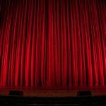 Red velvet theatre curtains lit from below stage
