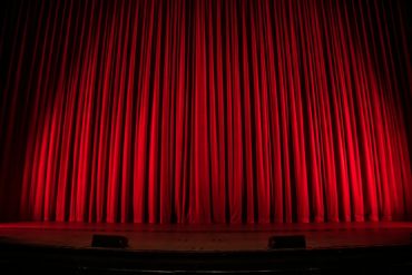Red velvet theatre curtains lit from below stage
