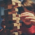 Young boy building a jenga tower with wooden blocks