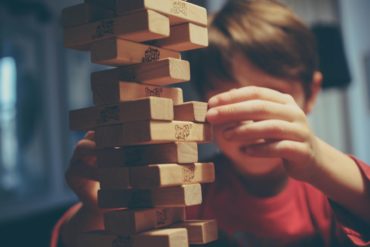 Young boy building a jenga tower with wooden blocks