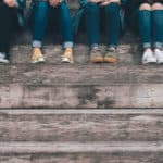 Teenage girls on steps, you can just see their feet and up to their knees. All are wearing sneakers and jeans
