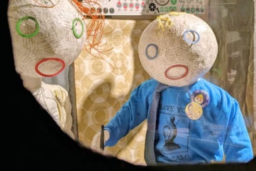 through the peeper of the windowless hut - showing two childlike models