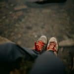 two people sat on a tree trunk wearing walking boots