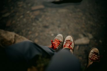 two people sat on a tree trunk wearing walking boots