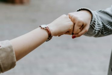 two young people bumping fists together