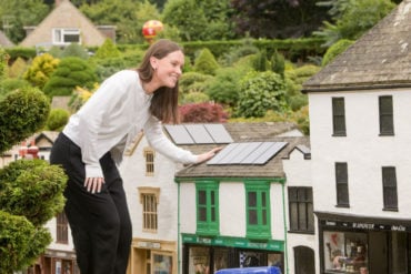woman looking at solar panels on model village