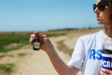 A women walking on a beach wearing RSPCA T-shirt and holding a dog collar