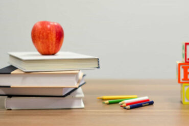 Books and apple and ABC blocks on a school desk
