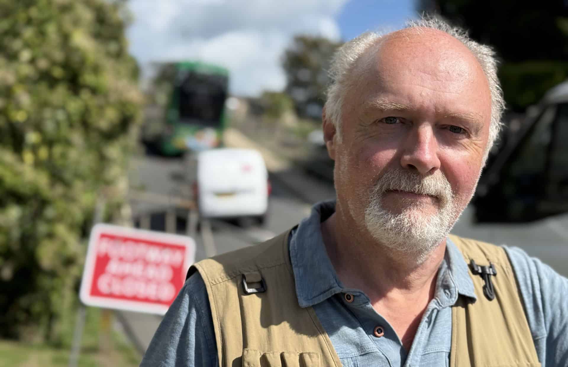 Martin Simpson with a bus and van going up the hill behind him