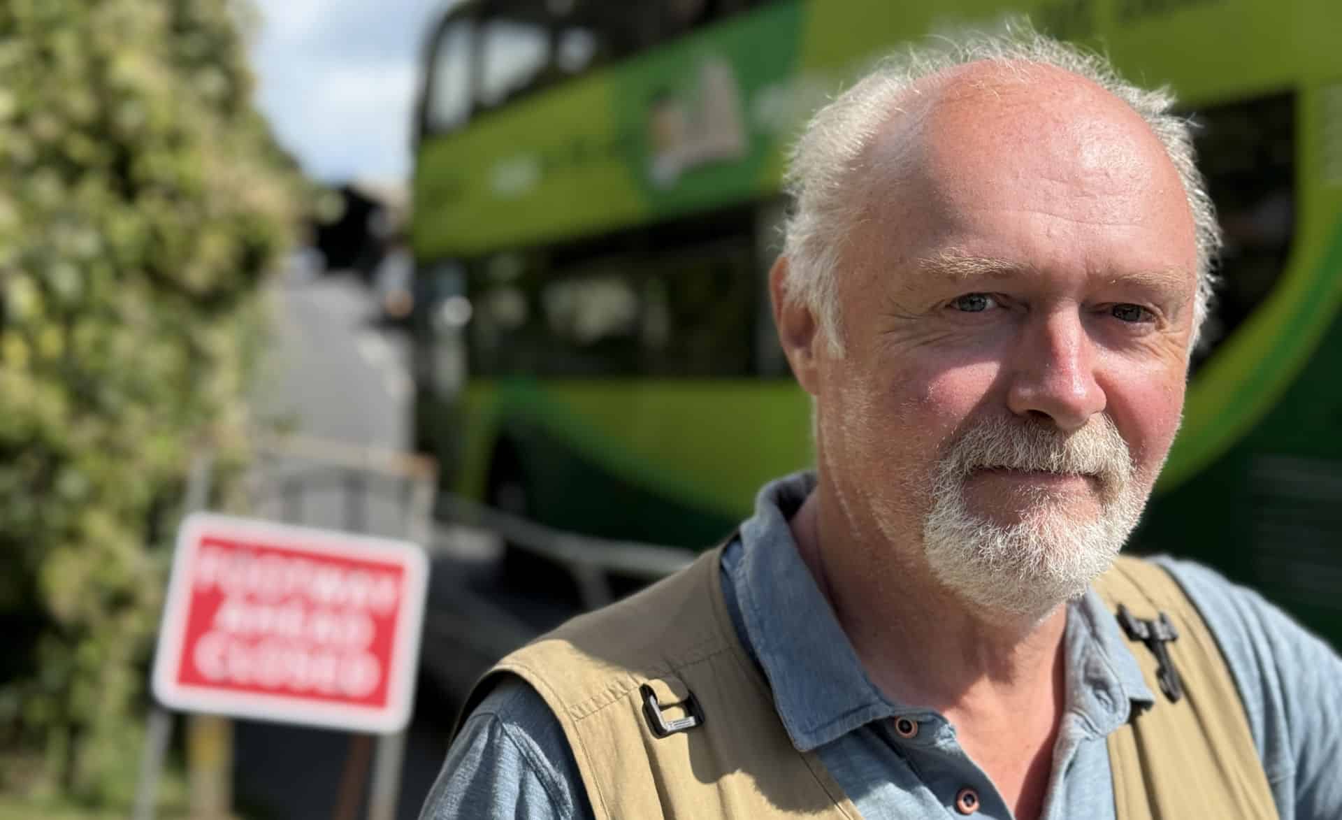 Martin Simpson with a bus going up the hill behind him