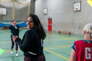 Women playing netball whilst smiling