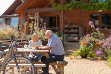 Older couple sitting in the garden of the Garlic Farm with bicycles next to their table