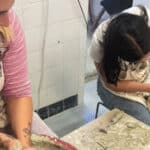 Two young women learning how to throw pottery on a potters wheel