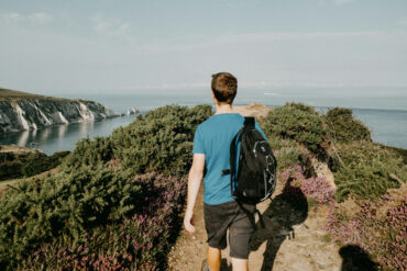 a man walking by headon warren on the Isle of Wight with countryside in the background