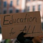person holding a placard that reads 'education for all'
