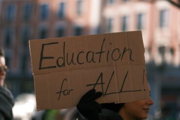 person holding a placard that reads 'education for all'