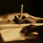sepia coloured photo of someone writing in a journal