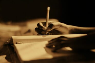 sepia coloured photo of someone writing in a journal
