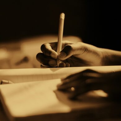 sepia coloured photo of someone writing in a journal