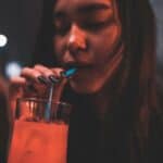 woman in a bar drinking her drink through a straw