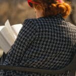 woman sitting on a bench in a park reading her book