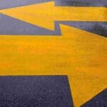 Two yellow arrows on tarmac facing in opposite directions