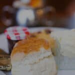 A Cream tea, with scones, butter, jam and clotted cream and a teapot with cup and saucer