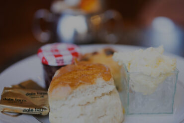A Cream tea, with scones, butter, jam and clotted cream and a teapot with cup and saucer