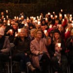 Mountbatten Isle of Wight's Light up a Life event in 2024 showing people sat on chairs outside holding candle lights