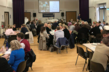People sitting in groups around tables in a hall