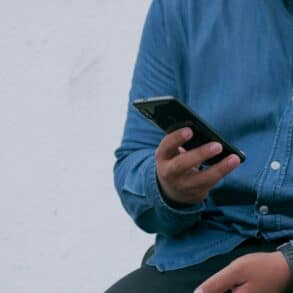 man in denim shirt sat down and looking at his mobile phone